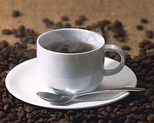 white ceramic teacup on saucer filled with black liquid